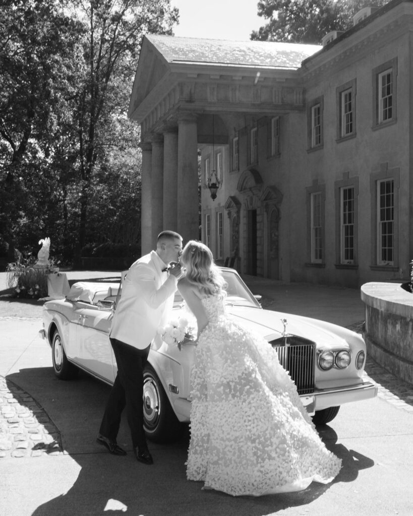 Bride and groom leaving Swan House wedding in vintage white Rolls Royce getaway car